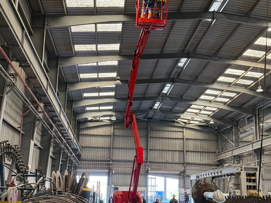 Nacelle articulée en intervention de maintenance sous la charpente d'un bâtiment industriel